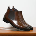 Men's Chelsea boots in brown with elasticated side panels and low heel on wooden surface
