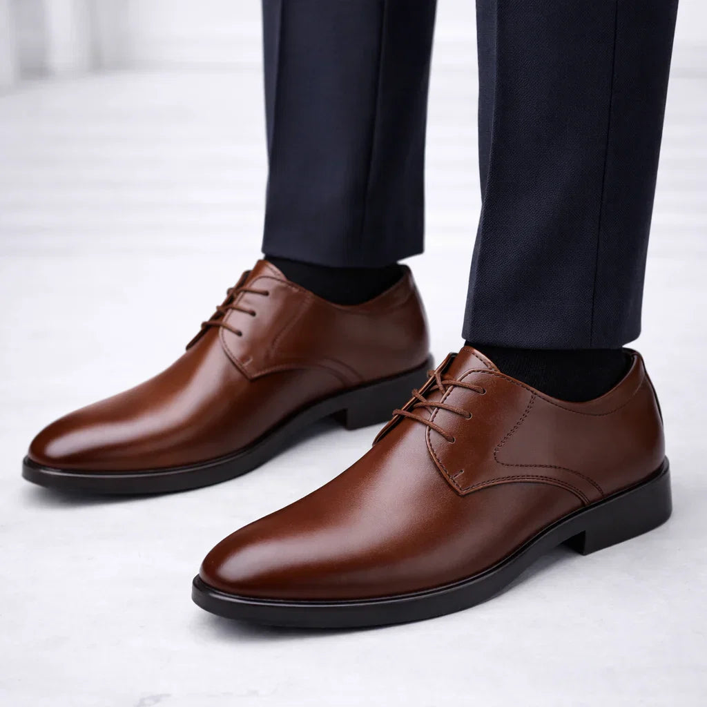 Men's formal derby shoes in brown with lace-up closure and smooth polished upper paired with tailored trousers