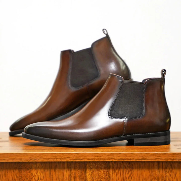 Side view of men's ankle-height Chelsea boots with smooth upper and elastic gussets