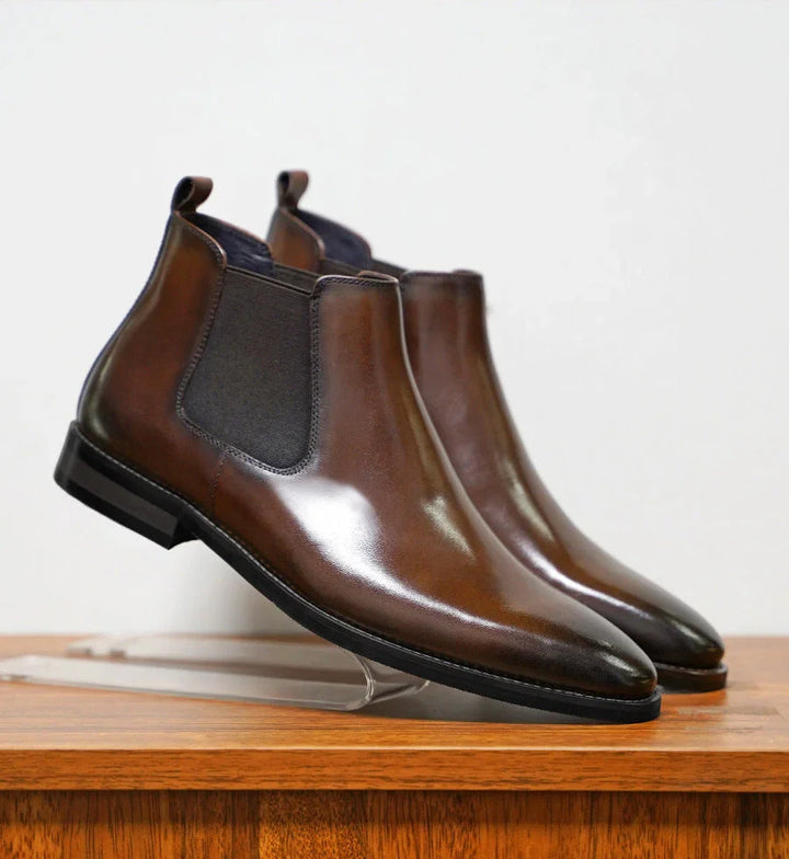 Men's Chelsea boots displayed on wooden surface showing sleek silhouette and ankle fit