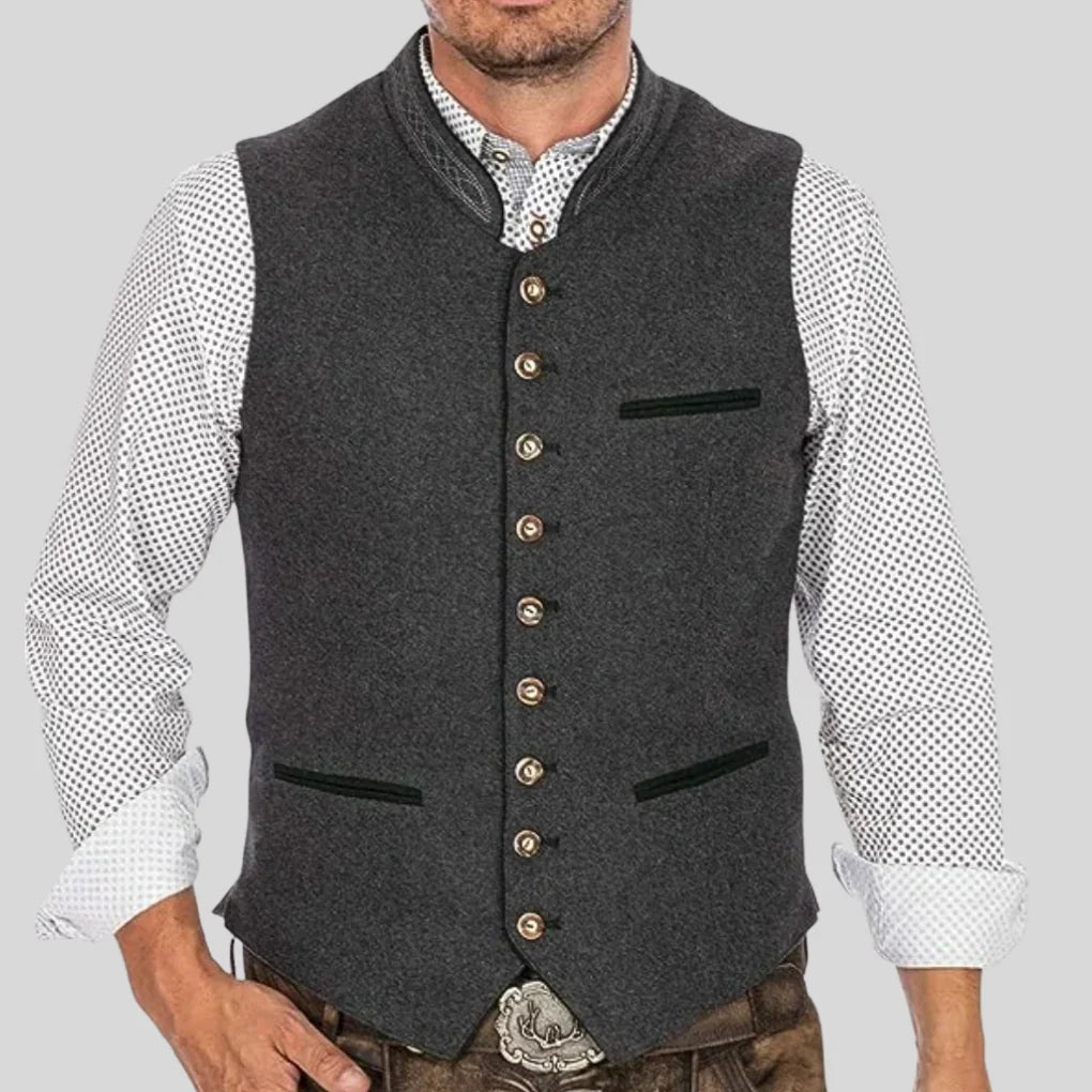 Men's charcoal Trachten waistcoat with standing collar, decorative button front, and contrast piping detail worn over patterned shirt