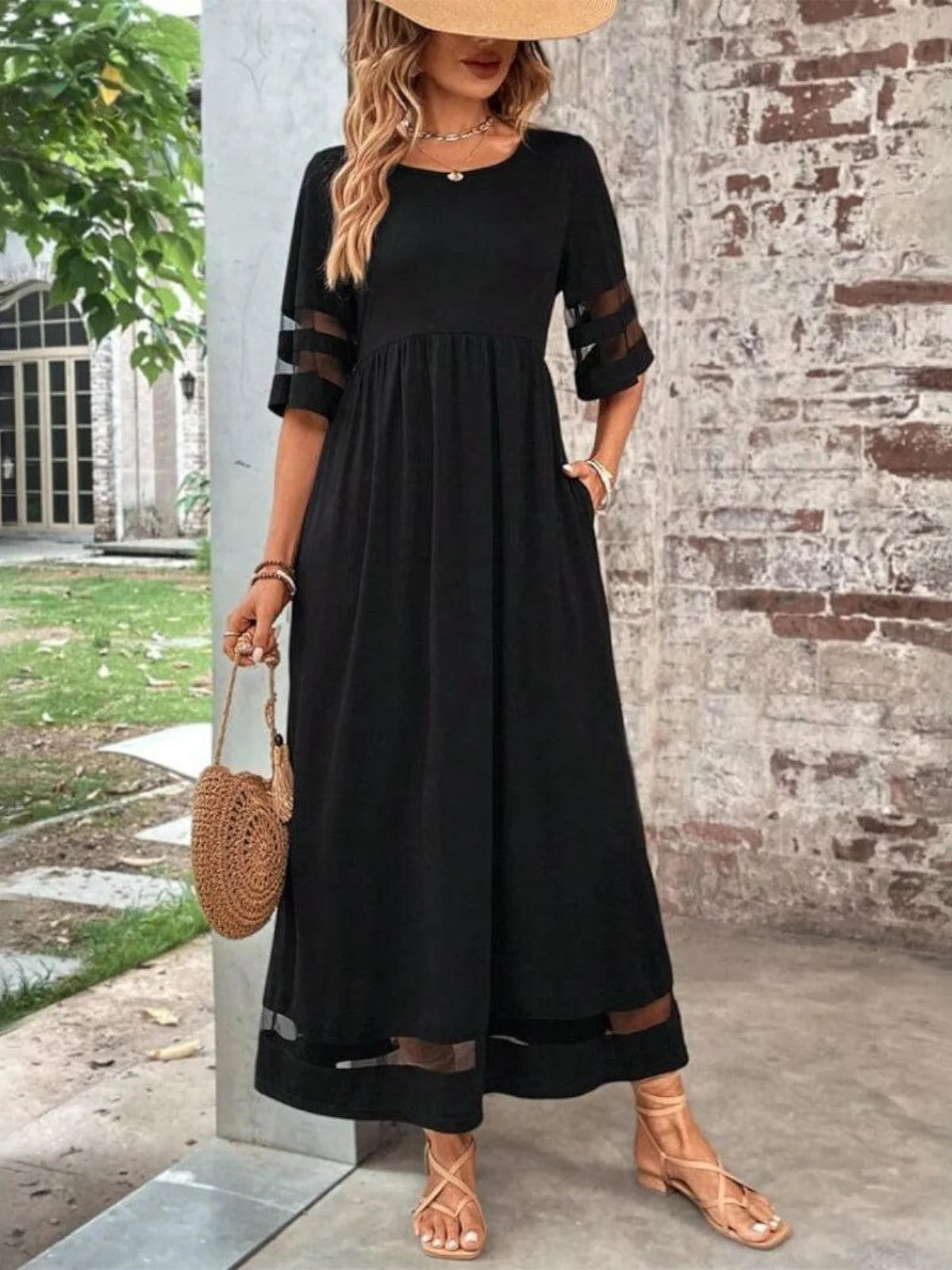 Woman wearing a flowing maxi dress with sheer mesh sleeve and hem panels in a casual outdoor setting