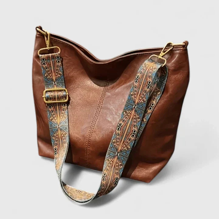 Beige bucket bag with decorative teal and metallic strap detail and adjustable buckle