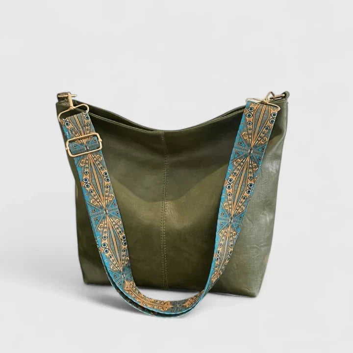 Convertible bucket bag showing adjustable wide strap with decorative embellishments