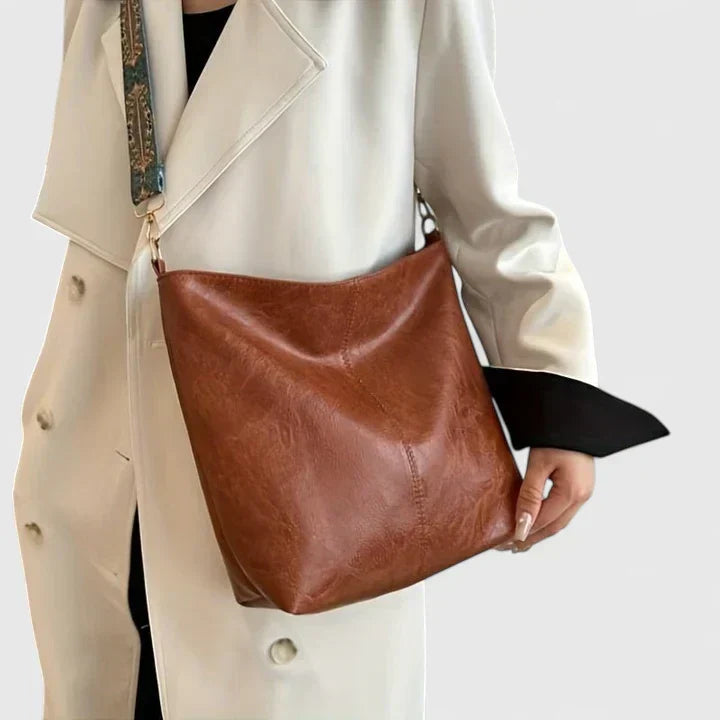 Women's slouchy handbag in neutral beige with structured base and decorative strap