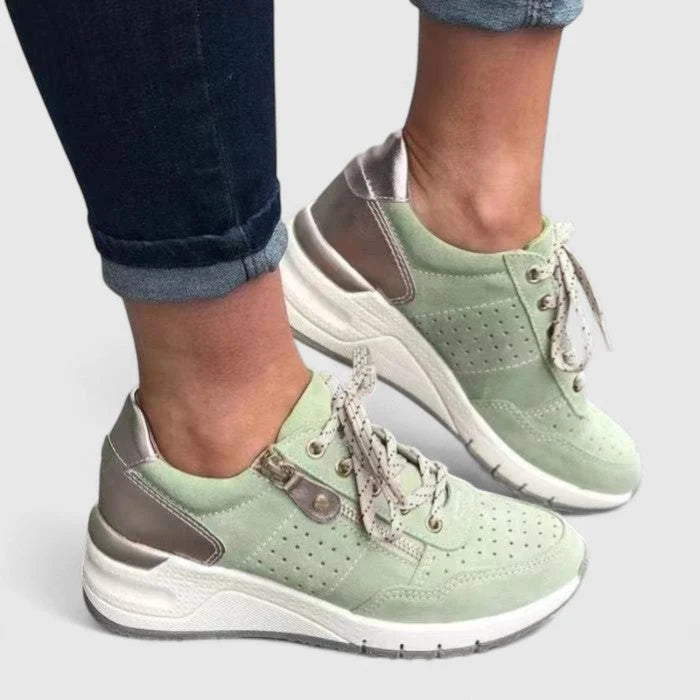 Women's orthopaedic trainers in mint green with chunky platform sole and lace-up front, worn with denim.