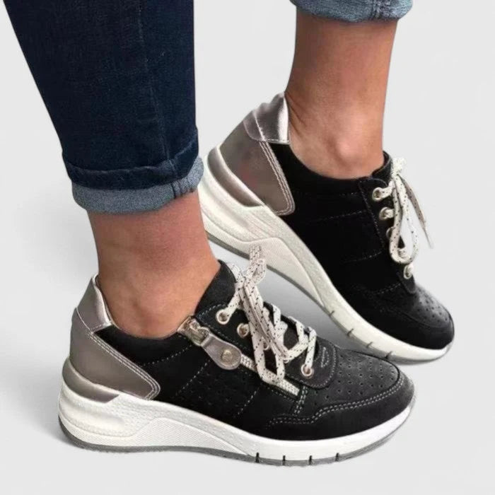 Close-up of women's orthopaedic trainers showing perforated detail and padded collar with metallic heel panel.