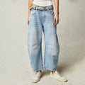Women's barrel leg jeans in light blue with curved silhouette and mid rise fit worn with trainers