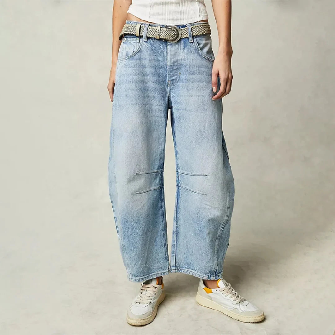 Women's barrel leg jeans in light blue with curved silhouette and mid rise fit worn with trainers