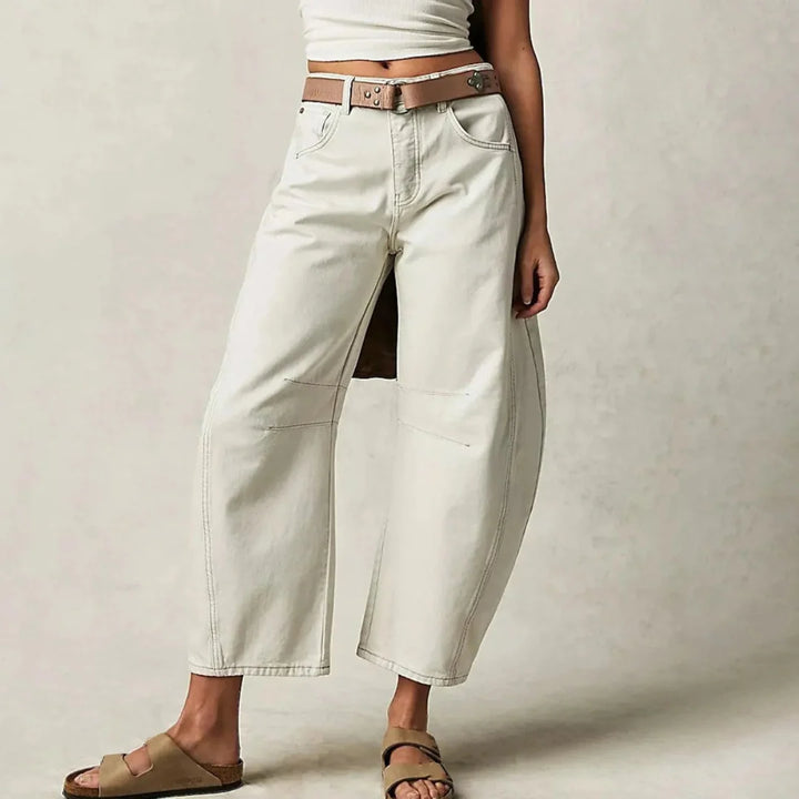 Side profile of women's barrel leg jeans displaying distinctive sculptural shape and cropped length