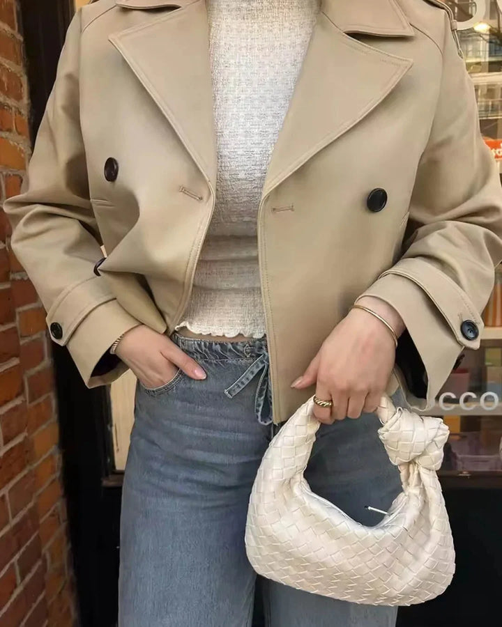 Detail of double-breasted button closure on women's cropped trench jacket