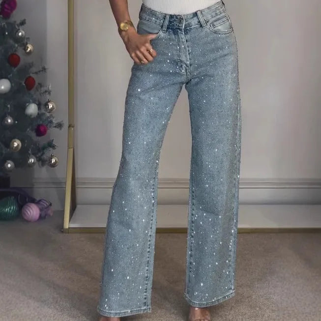 Close-up view of diamanté embellished wide leg jeans showing sparkle detail across light wash denim fabric