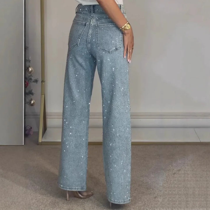 Side angle of high waisted embellished jeans with wide leg cut and allover diamanté detailing