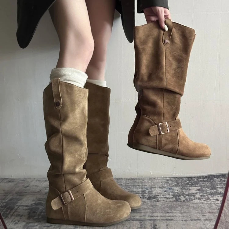 Model holding knee-high slouch boot displaying soft suede-effect texture and foldable design