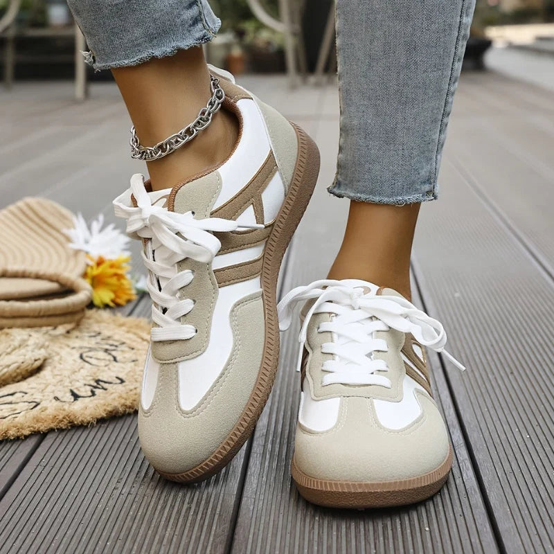 Women's wide-toe trainers in white and beige with lace-up front and gum sole worn with jeans