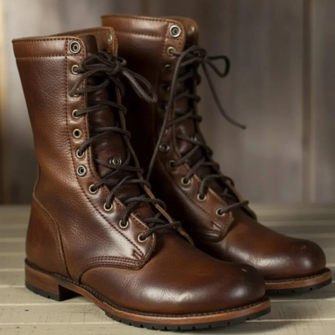 Women's lace-up mid-calf boots in brown with metal eyelets and flat sole on wooden floor
