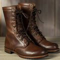 Women's lace-up mid-calf boots in brown with metal eyelets and flat sole on wooden floor