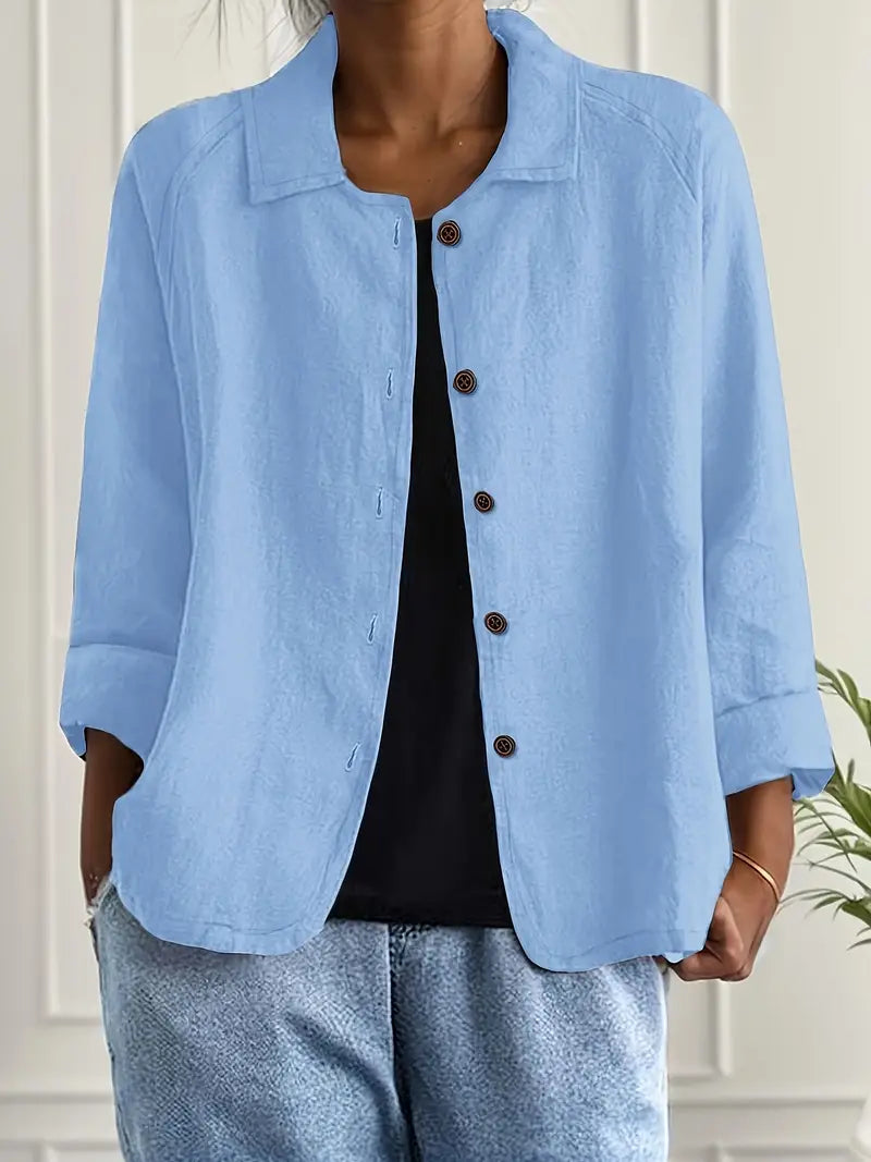 Women's button-front shirt in light blue with open collar and three-quarter sleeves, worn with black vest