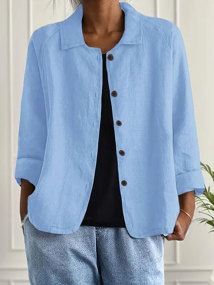 Women's button-front shirt in light blue with open collar and three-quarter sleeves, worn with black vest
