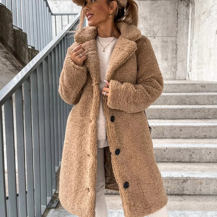 Woman wearing a beige oversized teddy coat with notched collar and button-front closure on outdoor steps