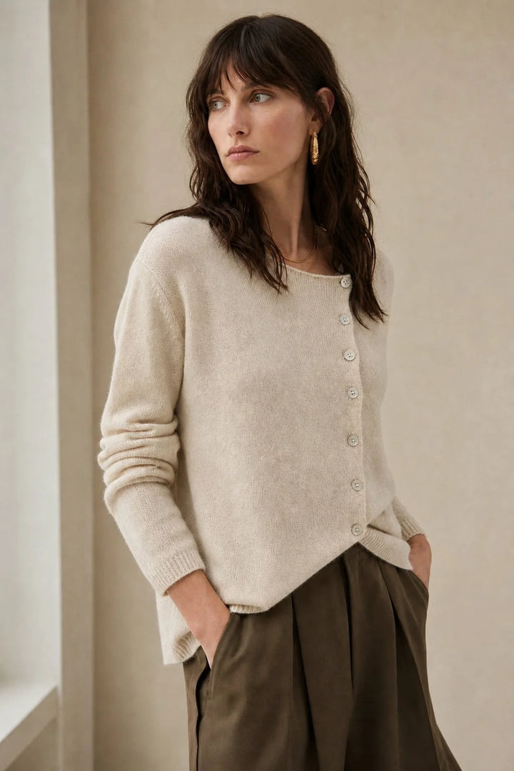 Model wearing a beige women's cashmere cardigan with asymmetric button detail and relaxed fit silhouette