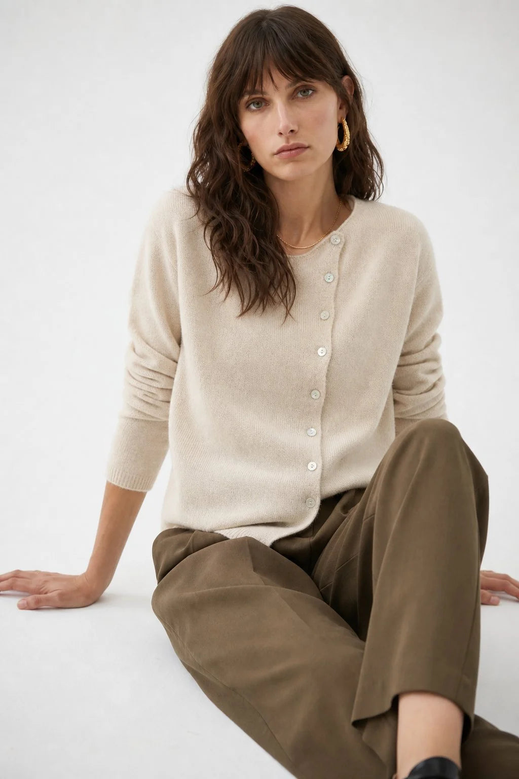 Front view of an asymmetric button cashmere cardigan with round neckline and hip-length cut