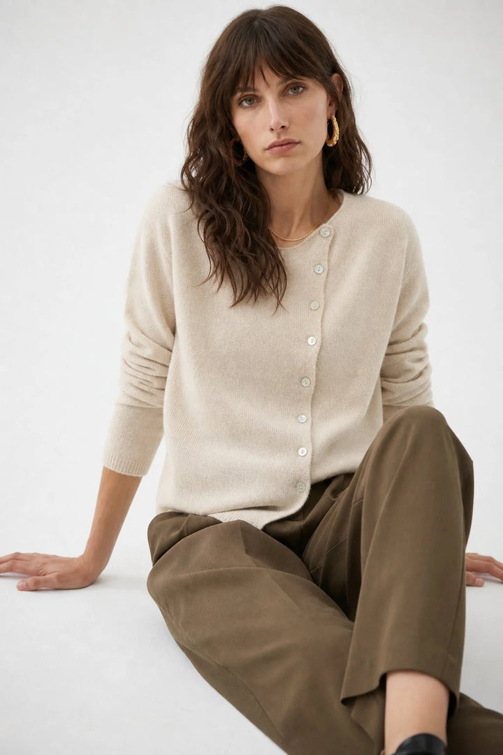 Front view of an asymmetric button cashmere cardigan with round neckline and hip-length cut
