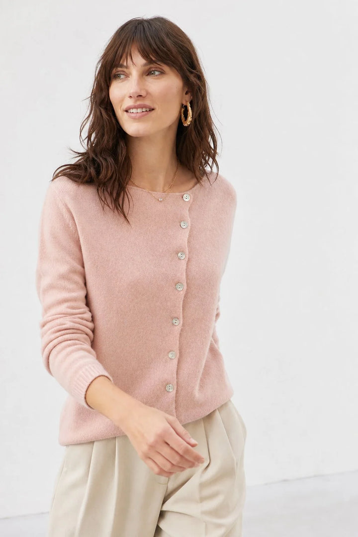 Full-body shot of a beige knit cardigan with asymmetric buttons paired with tailored separates