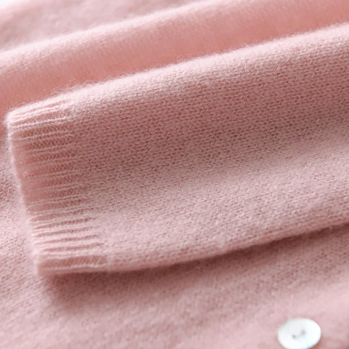 Detail of the asymmetric button closure and soft knit fabric on a beige cardigan