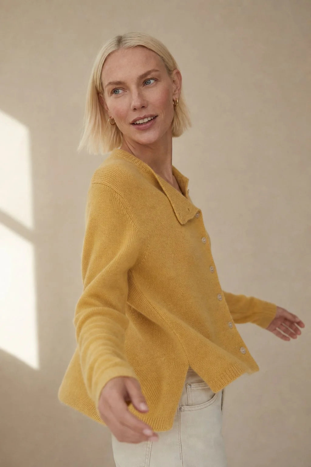Full-length view of a women's cashmere cardigan paired with tailored olive trousers