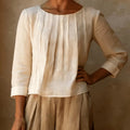 Women's pleated blouse with three quarter sleeves and round neckline in cream woven fabric with vertical pleats