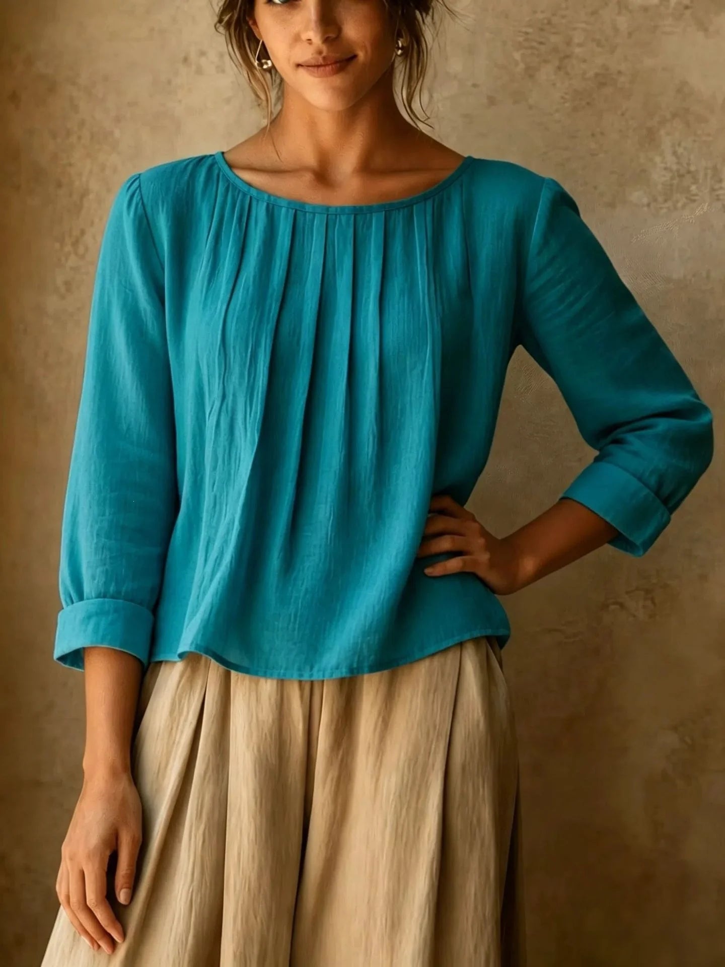 Detail shot of vertical pleats and round neckline on women's three quarter sleeve blouse in lightweight fabric