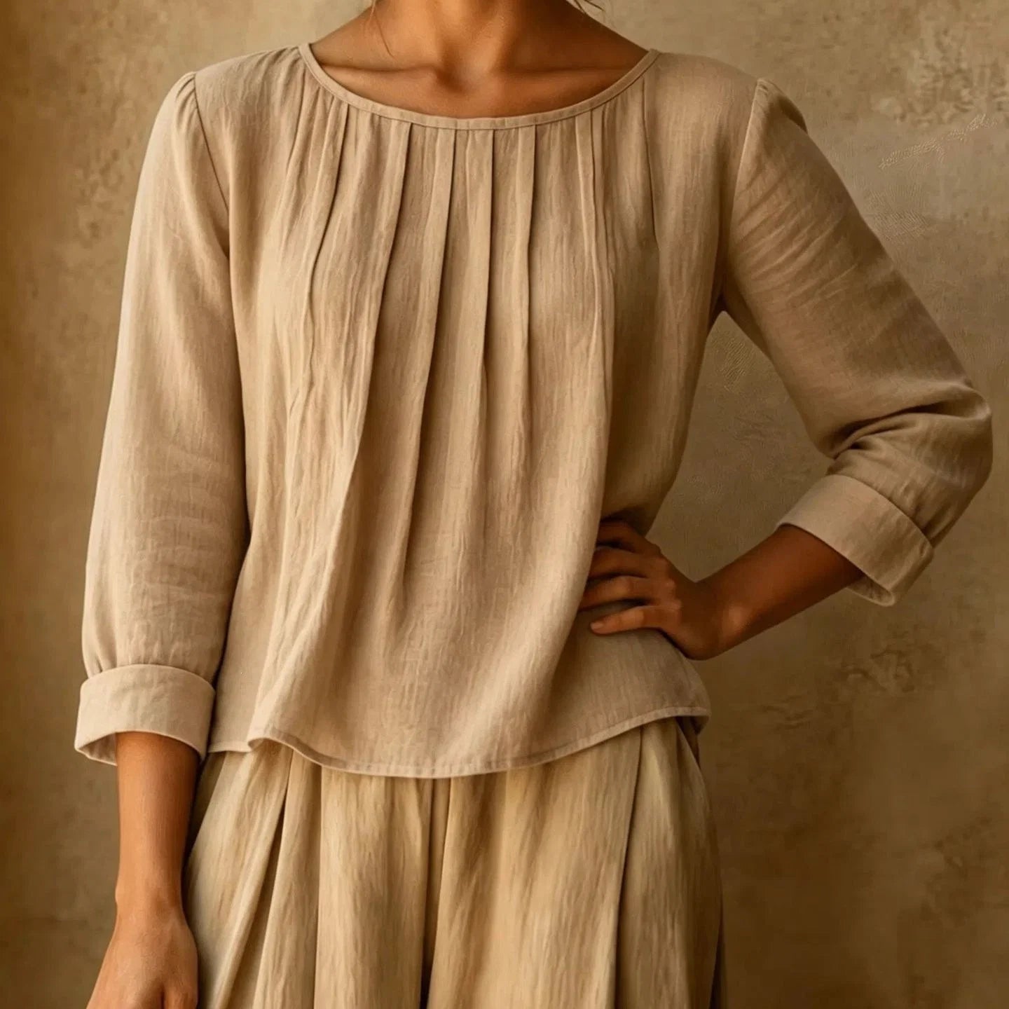 Close up of women's pleated blouse showing vertical pleats from neckline and three quarter sleeves with turned cuffs