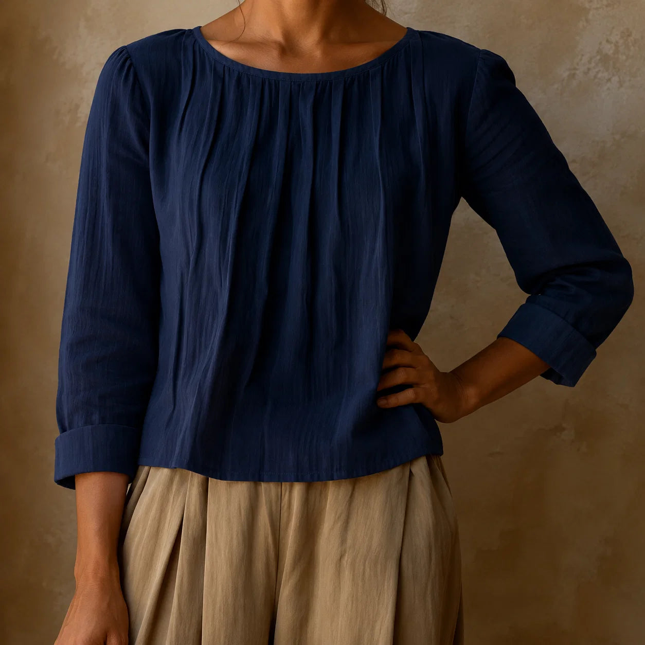 Detail of three quarter sleeves and turned cuffs on women's pleated blouse with round neckline