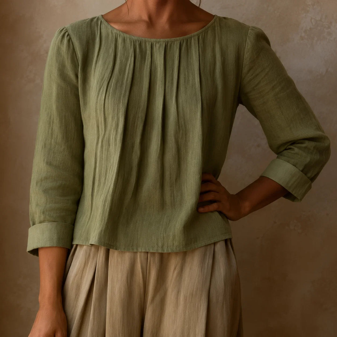Women's pleated blouse worn loose showing relaxed silhouette and vertical pleats from neckline in natural light