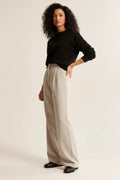 Women's high waist pleated trousers in beige paired with a black jumper for a polished look