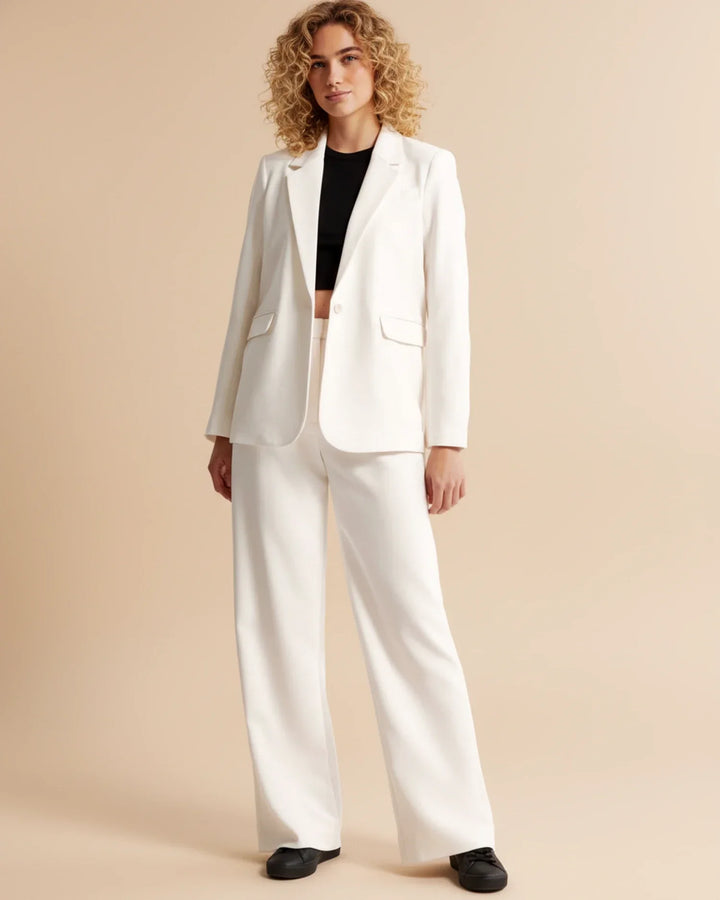 Detail view of front pleats on women's tailored trousers with smooth fabric drape