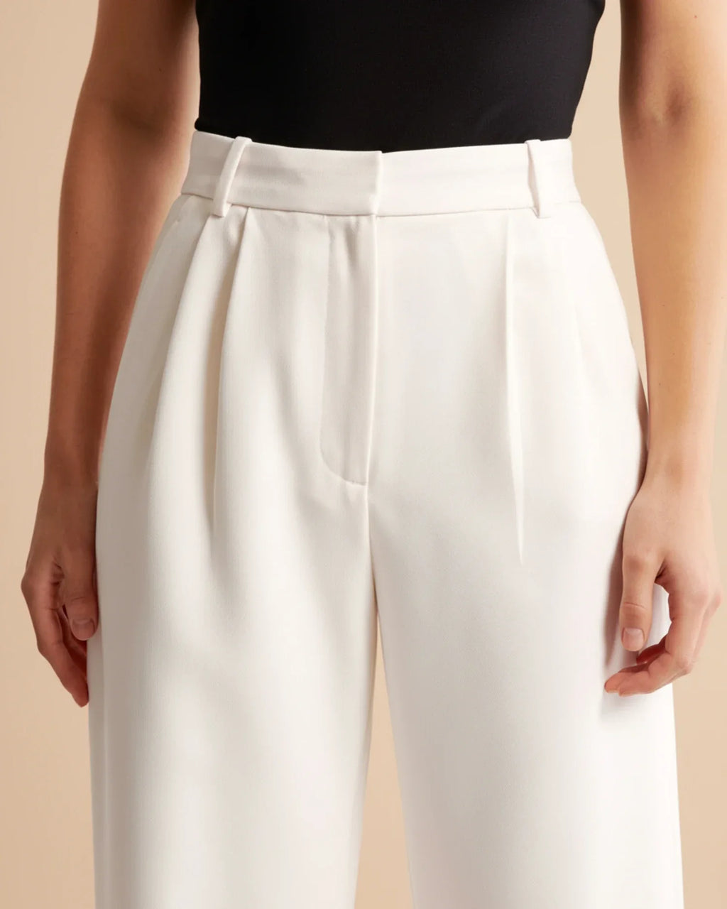 Women's beige pleated trousers styled with black top for polished everyday look