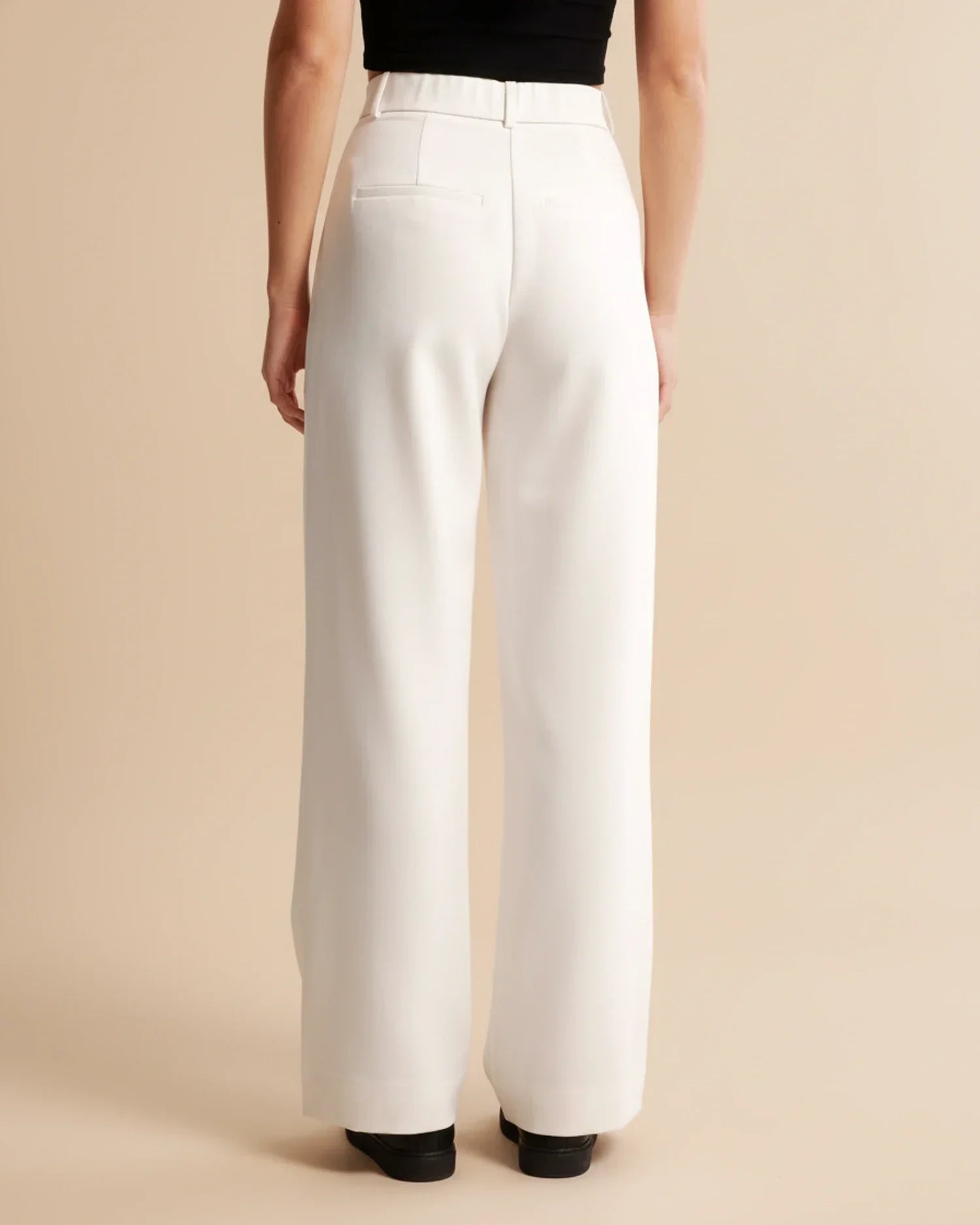 Full-length view of women's high waist pleated trousers in neutral beige tone