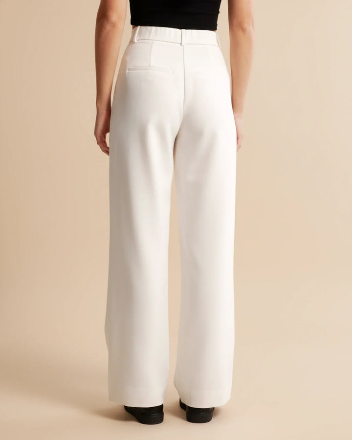 Full-length view of women's high waist pleated trousers in neutral beige tone