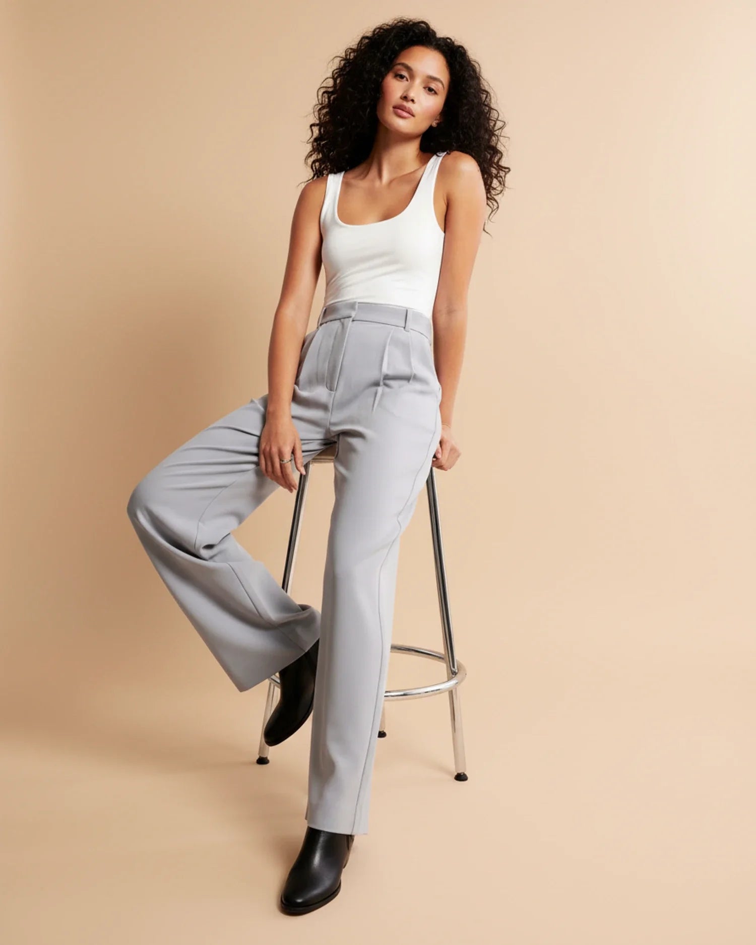 Detail shot of pleated trousers showing high waist and tailored straight-leg fit