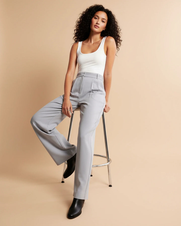 Detail shot of pleated trousers showing high waist and tailored straight-leg fit