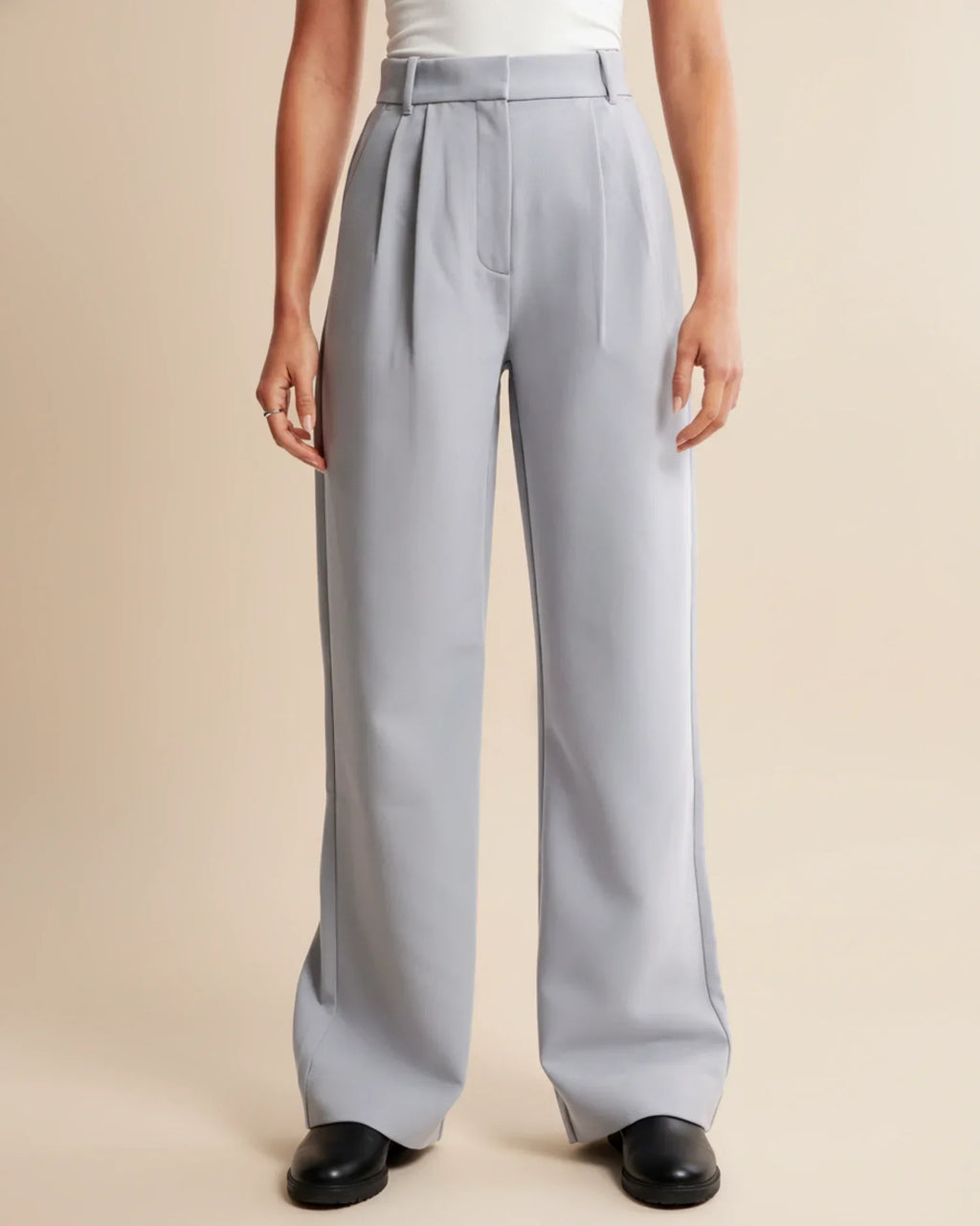Women's pleated trousers in beige paired with black jumper for versatile styling
