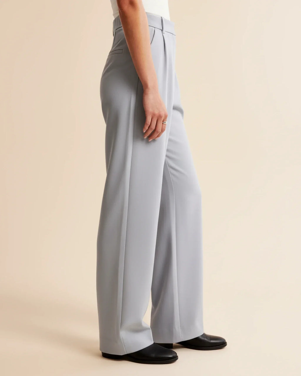 Side view of high waist pleated trousers with structured silhouette and clean finish