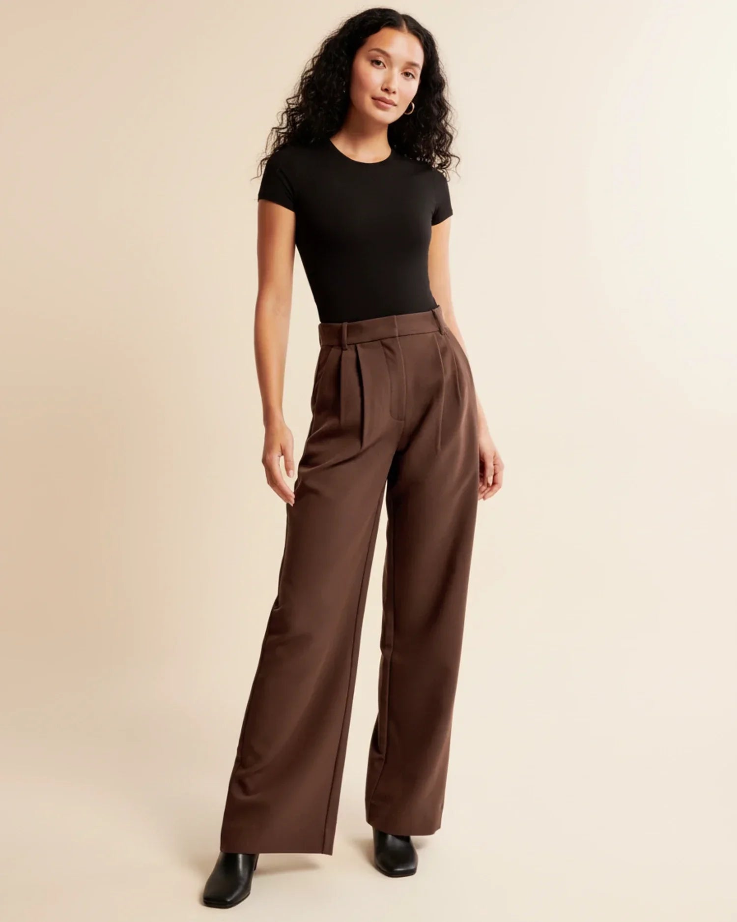 Detail view of tailored pleated trousers showing high-rise waistband and straight leg