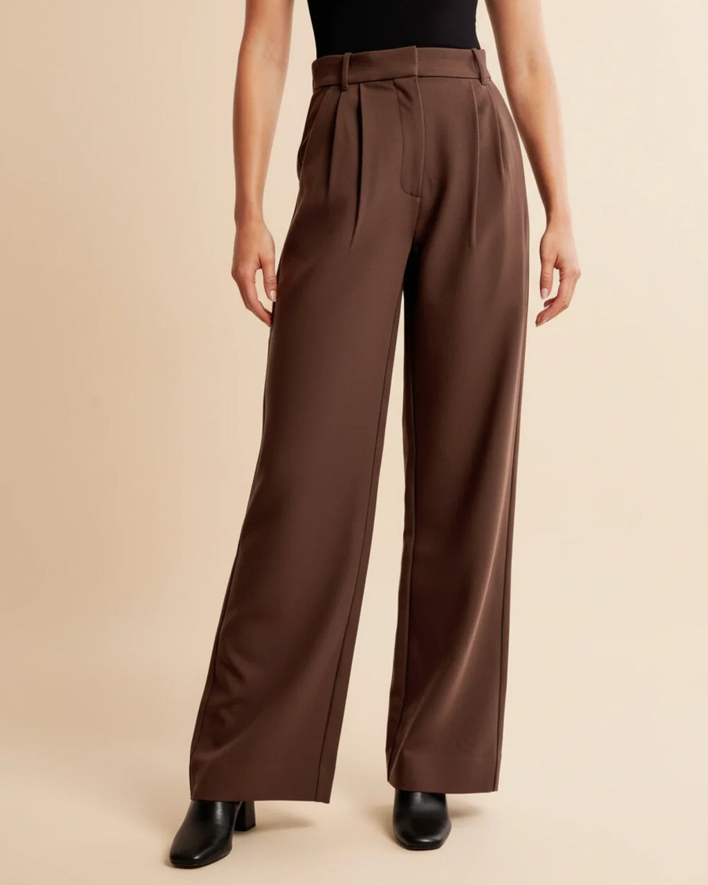 Women's beige pleated trousers with black jumper styled for work-to-weekend wear