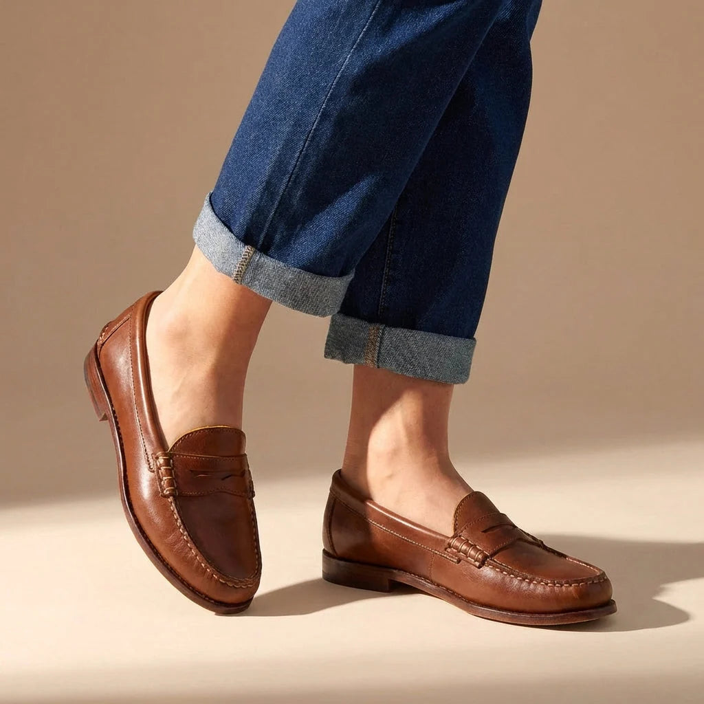Women's penny loafers in brown with moccasin stitching worn with rolled dark denim jeans