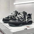 Men's chunky trainers in black with layered overlays and white laces on display shelf