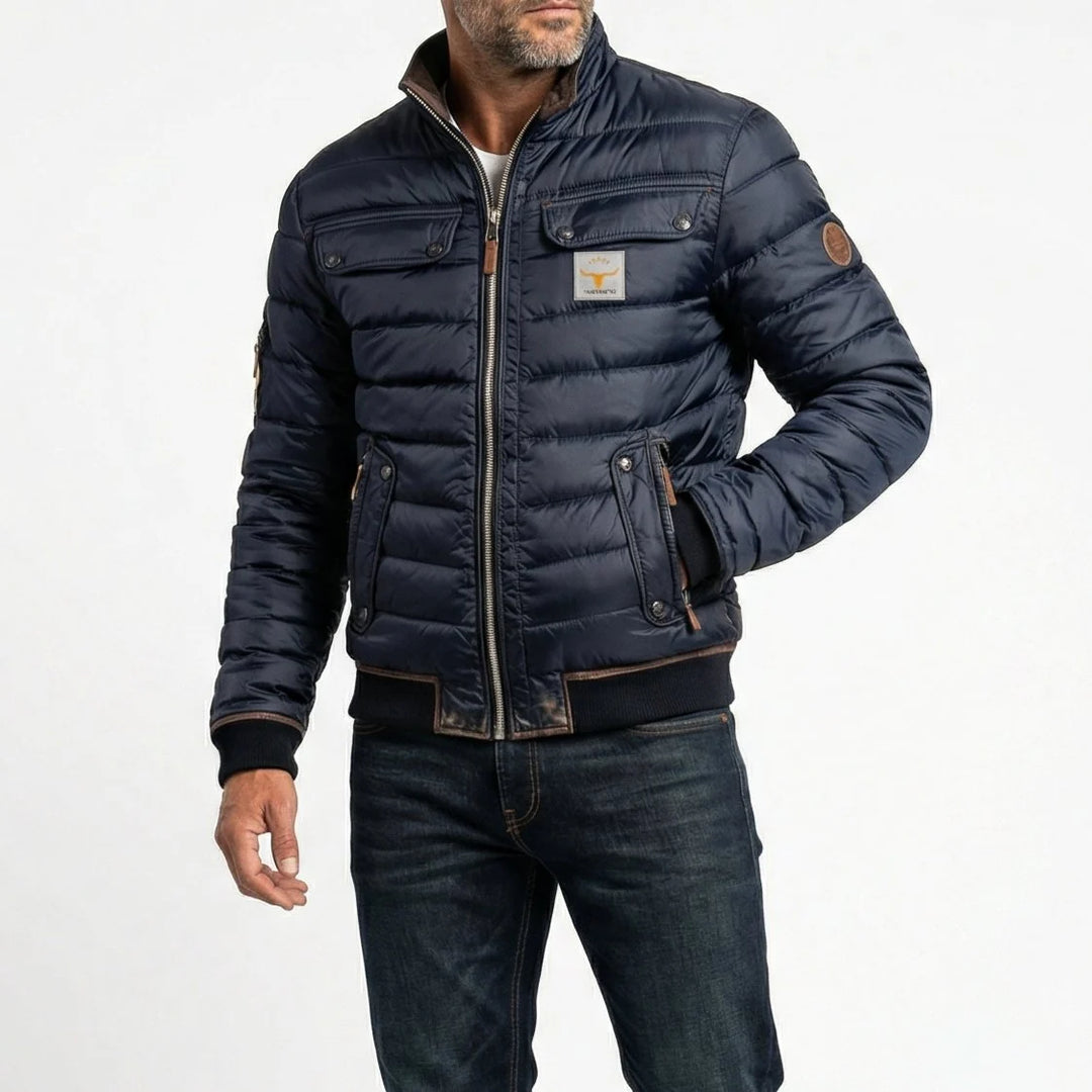 Men's navy quilted bomber jacket with stand collar and dual chest pockets, worn over casual attire