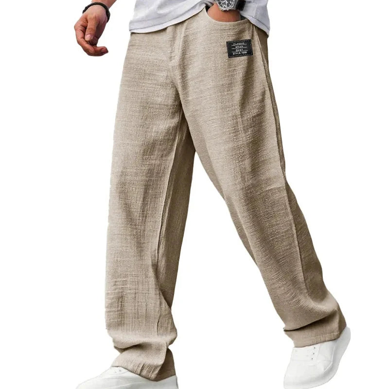 Full-length view of men's grey straight leg trousers paired with white trainers and casual top